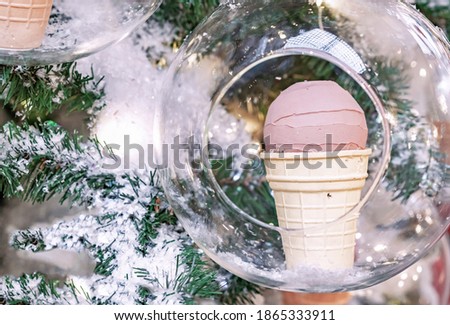 Chocolate ice cream in a waffle cup inside a transparent ball on a Christmas tree.