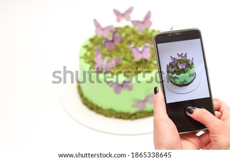 Woman's hand holds a phone and takes a picture of a beautiful cake