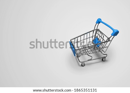 A miniature empty grocery basket in blue on a light gray background with space for text.