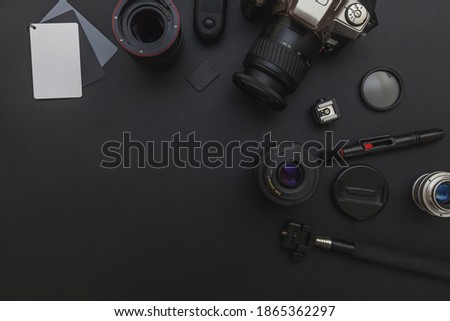 Photographer work place with dslr camera system, camera cleaning kit, lens and camera accessory on dark black table background. Hobby travel photography concept. Flat lay top view copy space