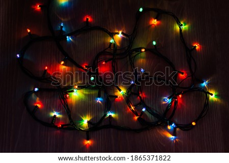 Christmas garland on a wooden background. Bright multicolored bunch of holiday lights. Christmas lights at night on the table. The concept of approaching Christmas. Decorations for the Christmas tree.
