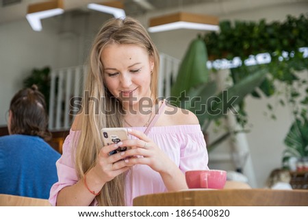 Woman sitting in cafe drinking coffee and planing her agenda on her phone. She alone in beautiful place, relaxing and dreaming about future