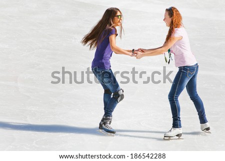 Image of group of teenagers on the ice holding hands and skating at the Medeo