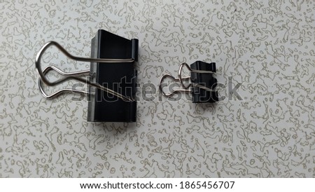 two large and small metal clips on a patterned gray background