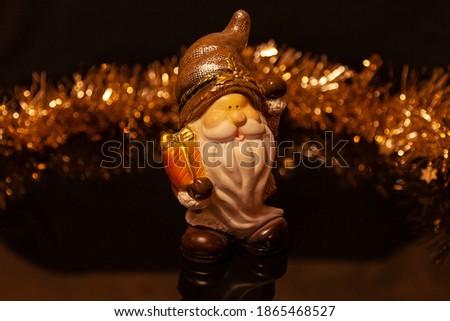 Glass decoration in the form of a gnome with a gift on black glossy glass