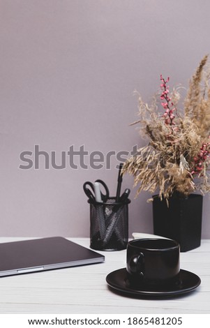 Cozy home work place. Laptop, office supplies, a bouquet of dried flowers on a gray table. Copy space