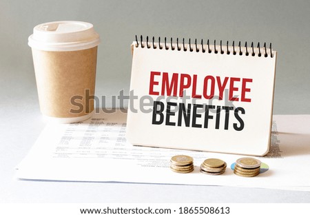 Hand with red pen. Cofee cup. Stick. Keyboard and white background. Employee Benefits sign in the notepad