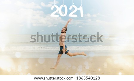 New Year concept. A man in shorts runs along the beach against the background of the sea. Inscription 2021