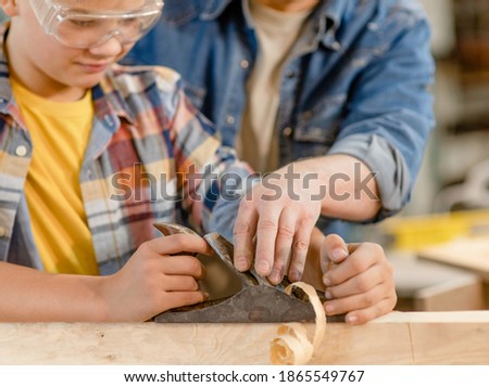 Father teaches son to plan a wooden block