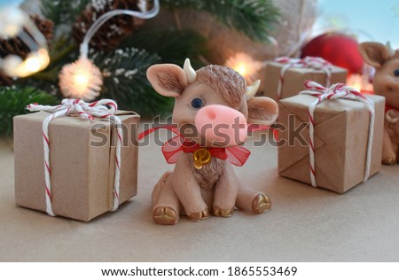 Greeting holiday card with cute toy calf and gifts on festival background. Chinese new year. Symbol 2021.