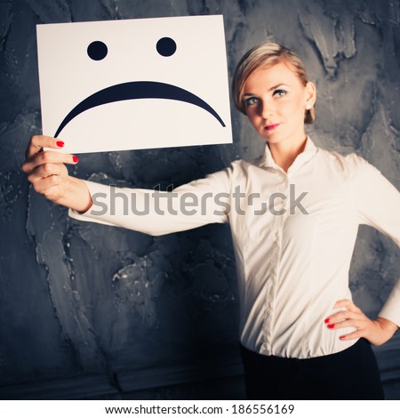 Young business woman holding paper with unhappy, sad smiley. Photo in color style instagram filters