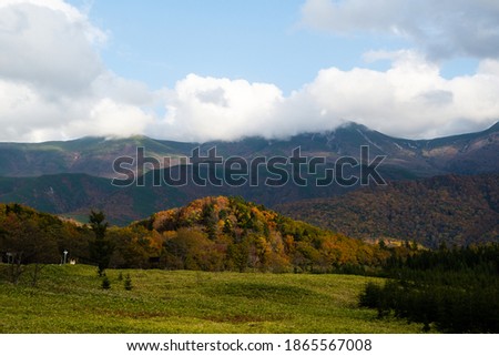 Clouded Shiretoko Mountains and the site of reclaimed land with autumn leaves in autumn, Shari, Shiretoko, Hokkaido, Japan