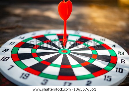 Close up red color arrow in the center of Bullseye with dark background concept of business goal, genius and capability.