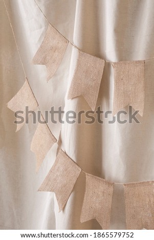 Close-up of a garland of decorative flags to decorate the photo zone on a beige background. Festive background decoration for birthday celebration. Selective focus