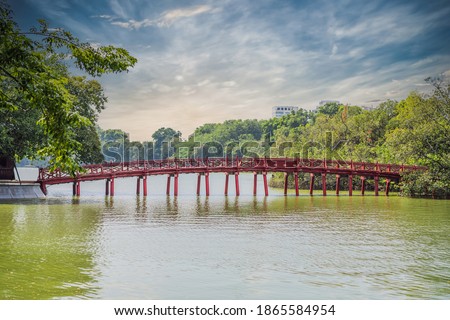 The Red Bridge in public park garden with trees and reflection in the middle of  Lake in Downtown Hanoi. Urban city at sunset, Vietnam. Cityscape background Royalty-Free Stock Photo #1865584954