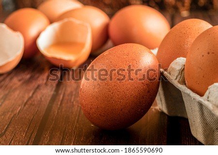 Close-up view of raw chicken eggs on wooden background. Fresh farm egg. Eggs in carton box. Broken egg with yolk.