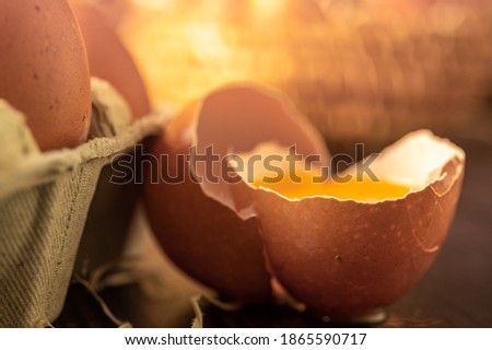 Close-up view of raw chicken eggs on wooden background. Fresh farm egg. Eggs in carton box. Broken egg with yolk.