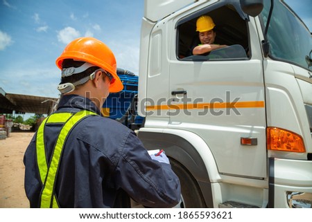 Asian foreman with safety hats and safety vest is carrying a car inspection document in the parking with truck drivers,Concept of planning work day. Road transport safety concept
