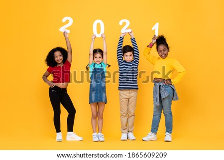 Cute mixed race kids smiling and holding 2021 numbers isolated on yellow background for new year concepts Royalty-Free Stock Photo #1865609209