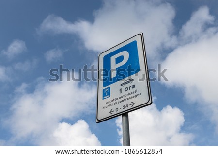 Parking sign with time limit one hour except authorized, isolated on a blue sky with white clouds.