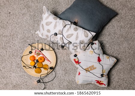 Tangerines and cookies on a plate with pillows for the new year