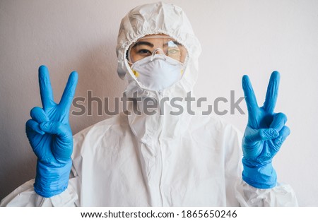 Healthcare worker wearing PPE suit with mask for protect virus and showing victory sign. PPE while protecting healthcare workers from exposure to the COVID-19 virus in healthcare settings.
