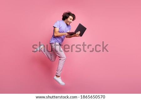 Full size profile photo of brown haired bristled trendy stylish man jump run hold laptop wear violet t-shirt isolated on pink color background Royalty-Free Stock Photo #1865650570