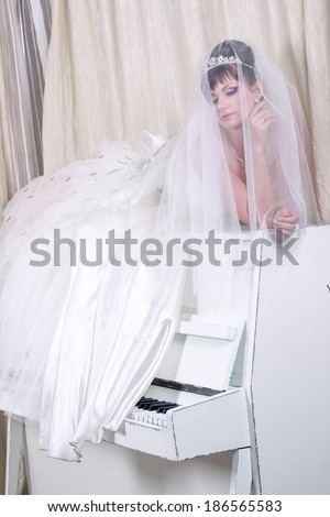 Beautiful woman in luxurious dress lying on the piano