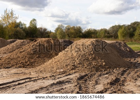 Mountain of sand at a construction site. Foundation material. Soil prepared to strengthen the soil. Earthen heap. Fine sand to create a concrete mortar. Royalty-Free Stock Photo #1865674486
