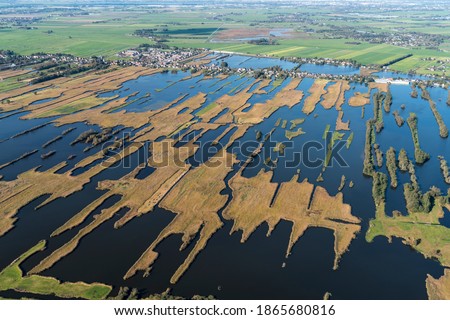 Aerial view of nature reserve area Lake Nieuwkoopse Plassen in The Netherlands in autumn colours. On the horizon village Noorden with houses and farmland.