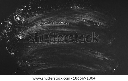 Black background sprinkled with flour, smeared flour, table for cooking, rolling dough. Blank space for menu text, recipe, ingredients. Chalk board and rubbed stains. Royalty-Free Stock Photo #1865691304