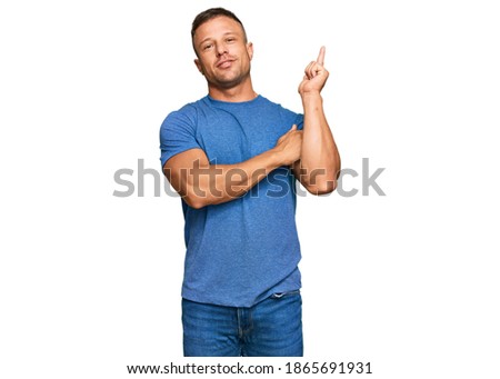 Handsome muscle man wearing casual clothes with a big smile on face, pointing with hand and finger to the side looking at the camera. 