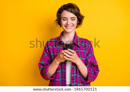 Photo of happy young woman addicted user hold phone wear plaid shirt isolated on shine color background