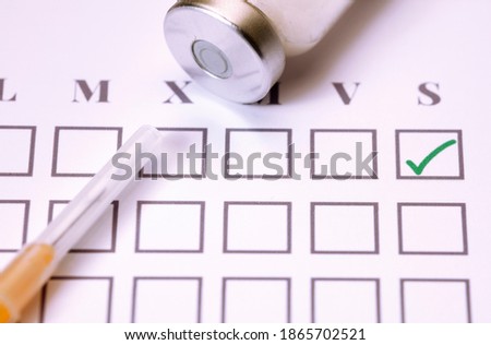 Vaccine vial, syringe, on top of monthly calendar 2021,