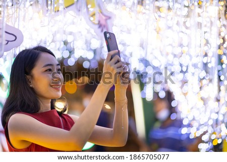 Asian female using smartphone for taking a photo of Christmas festival in town.
