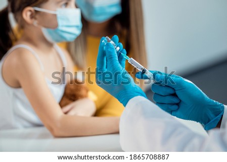Close-up of pediatrician preparing a vaccine for a child during coronavirus pandemic.  Royalty-Free Stock Photo #1865708887