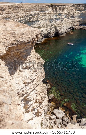 Summer seascape. Very beautiful view of the Black Sea of emerald color and pleasure boats from the height of the rocky coast. The inscription on the boat in Russian Crimea.