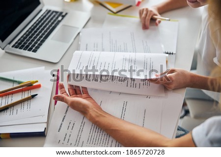 Parent helping her teenage daughter with understanding the grammatical topic from a schoolbook while working at a cluttered desk Royalty-Free Stock Photo #1865720728