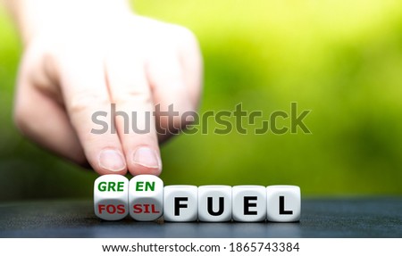 Hand turns dice and changes the expression "fossil fuel" to "green fuel". Royalty-Free Stock Photo #1865743384