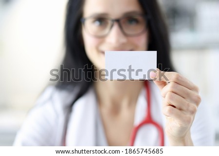 Smiling doctor portrait holding white business card in hand. Dental clinic services concept