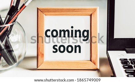 COMING SOON text in wooden frame on office table.