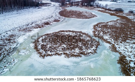 Aerial view of countryside and frozen brook in winter. 