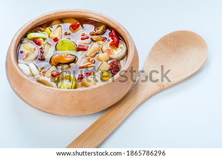 Traditional Thai Tom Yam soup in wooden bowl on table.