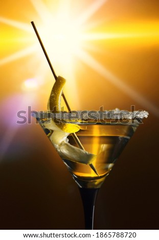 Dirty martini with a lemon twist on a yellow background.
