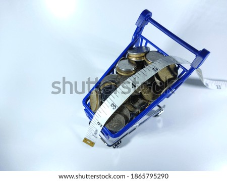 Selective focus.Blue trolley,coins and measuring tape isolated on white background.Shopping and money concept.