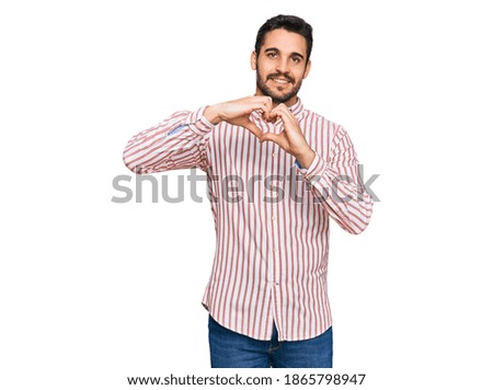 Young hispanic man wearing business shirt smiling in love doing heart symbol shape with hands. romantic concept. 