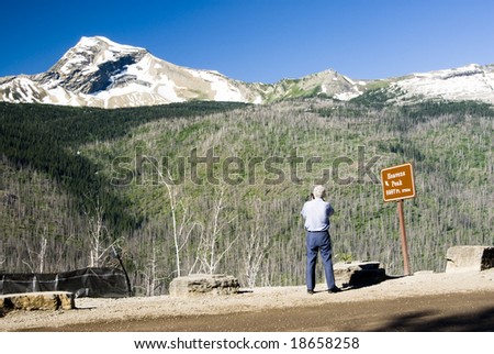 a tourist taking a picture of Heavens Peak in Glacier National Park.