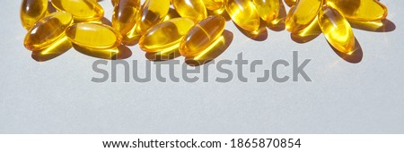 Omega3 gel capsule. Sun shadow. Yellow vitamin. Health eating. Dietology drug. Fish oil supplement. Nurtitional concept. Golden color softgel collagen. Grey background. Medicine immunity cosmetics