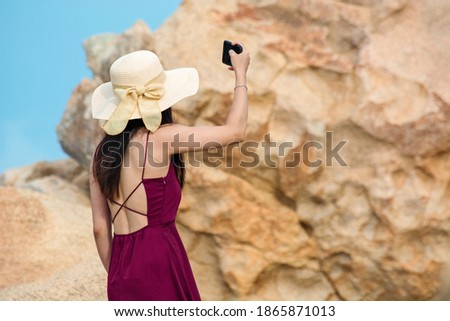 Girl in hat takes pictures of herself on the phone in the mountains