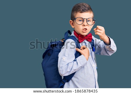 Cute blond kid wearing nerd bow tie and backpack annoyed and frustrated shouting with anger, yelling crazy with anger and hand raised 